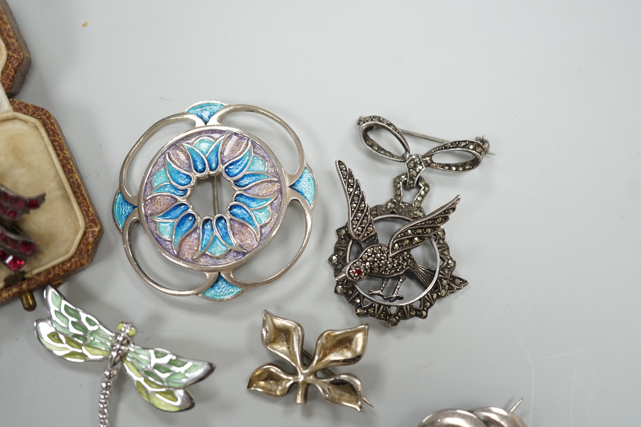 An early 20th century white metal and foil backed garnet cluster set bird brooch, 27mm and eight other assorted mainly 925 brooches including two enamelled and one Finnish yacht brooch.